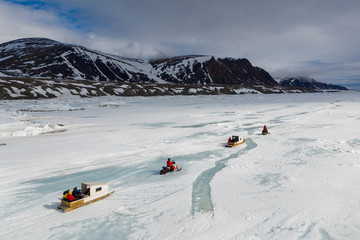 Aerial drone photo of tourists travelling by Qamutiik on the sea ice near Sirmilik National Park in Nunavut, Canada