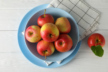 Composition with plate and apples on white wooden background, top view