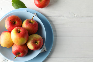 Composition with plate and apples on white wooden background, top view