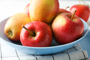 Plate with apples on kitchen towel, close up