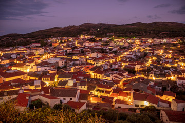Obraz premium overview of the village of montanchez in the evening with the illuminated streets and the colored sky, extremadura, caceres, spain