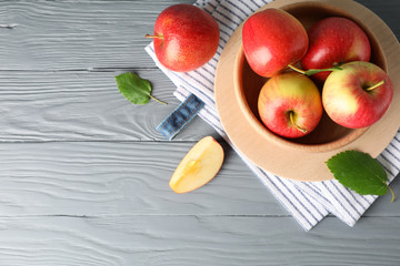 Bowl with apples on wooden background, top view