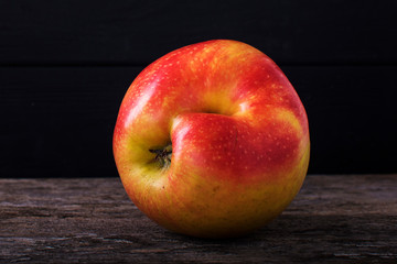 One red apple close up and copy space on the background of a rusty table. An ugly apple with rot.