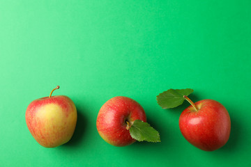 Flat lay with red apples on green background, space for text