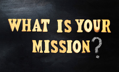 Fototapeta na wymiar What is your mission? Words composed with wooden letters on a blackboard or chalkboard, business concept