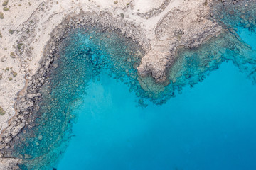 An aerial view of the beautiful Mediterranean sea, where you can se the rocky textured underwater corals and the clean turquoise water of blue lagoon Agia Napa