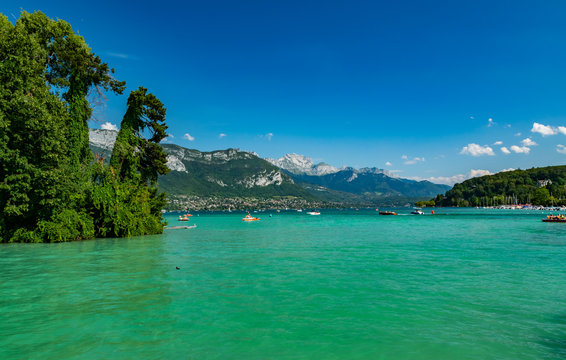 View of Annecy lake, boats with tourists and Alps mountains on sunny day with blue sky in Annecy city.Annecy is the largest city of Haute-Savoie department.