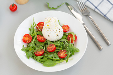 Fresh Salad with Italian burrata cheese, arugula, cherry tomatoes and olive oil. Healthy eating. Selective focus 