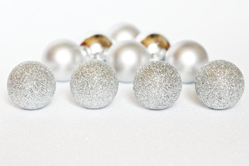 Shiny Christmas tree decorations lie on a white sparkling surface imitating freshly fallen snow and snowdrift. Happy New Year and Merry Christmas.