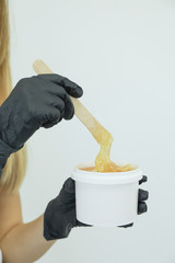 Woman holding liquid yellow paste for shugaring against white background, copy space