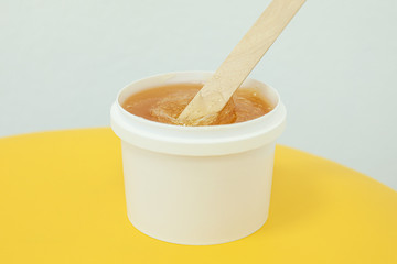 Liquid yellow paste for shugaring on yellow background, space for text