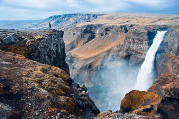 Hiker standing on the cliff overlooking Haifoss waterfall