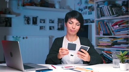 The designer at the office desk reviews photos - Powered by Adobe