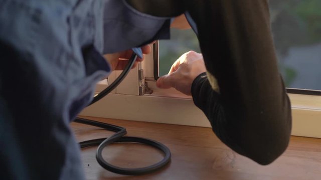 The professional master changes the rubber gaskets and seals on the pvc window. Preparing for winter, warming the house. Window repair. Window sealing
