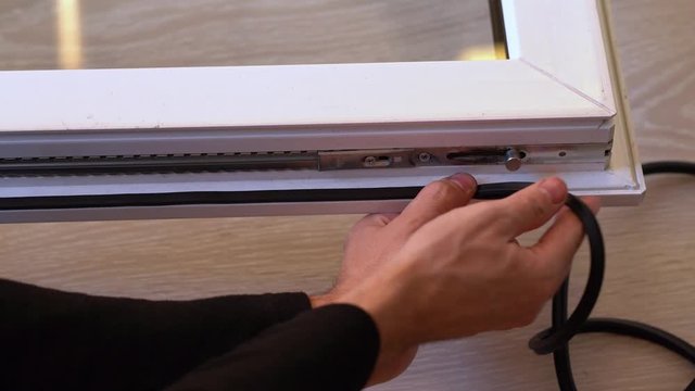 The professional master changes the rubber gaskets and seals on the pvc window. Preparing for winter, warming the house. Window repair. Window sealing