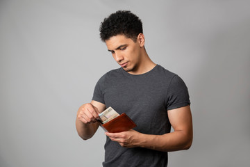 Young Hispanic man checking his wallet - sad man watching his money