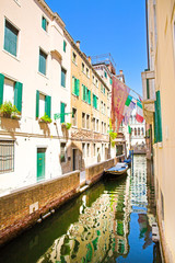 Obraz premium Amazing view to the narrow canal in Venice, Italy. Old buildings reflect in green canal water. 