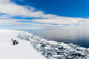 Aerial drone photo of tourists visit the floe edge near Sirmilik National Park in Nunavut, Canadaa © Colin