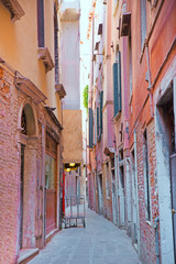 Fototapeta na wymiar Beautiful narrow street in Venice, Italy. PInk and orange facades of old buildings. 