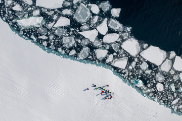 Aerial drone photo of tourists visit the floe edge near Sirmilik National Park in Nunavut, Canadaa
