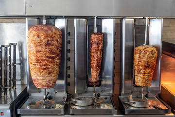 Stacked meat roasting on rotating vertical spit for gyros