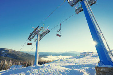 Ski lift with seats going over the mountain and paths from skies and snowboards. Beautiful winter...