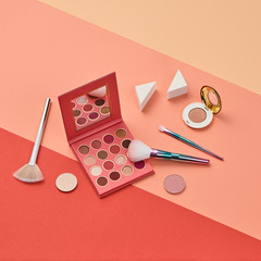 Fashion beauty product layout. Woman Essentials cosmetic makeup Set. Collection beauty accessories. Trendy Eye shadow, Brushes, lipstick. Coloful coral art Flat lay. Creative make up artist concept