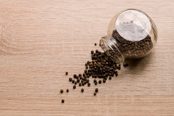 Black Pepper Peas Scattered On The Table From A Glass Jar. Close Up. Macro. Top View.