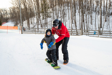 Young boy takes a snowboarding lesson