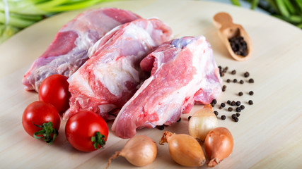 Raw meat slices on chopping board with fresh vegetables and spices
