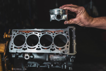 Engine cylinder in the hands of a mechanic. Car engine repair in the garage.