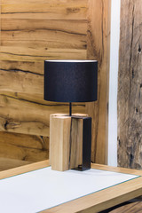 Wooden table lamp made of a piece of wood spruce, a natural original lamp. Glowing bulb wooden table lamp in the interior