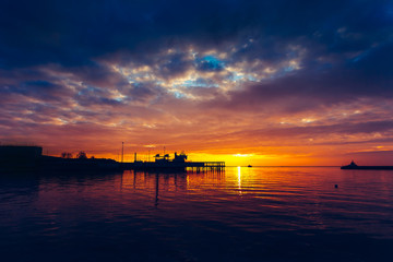 Obraz na płótnie Canvas Harbor and boat under a colorful sunset.