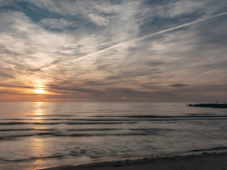 landscape with defocused beautiful dramatic golden sky over the sea, reflection at sunset time, long exposure 