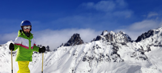 Fototapeta na wymiar Young skier with ski poles in snow mountains at sun winter day