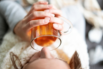 Disease. Cheer at home. A young woman is sick, is treated at home. Black tea with lemon in a...