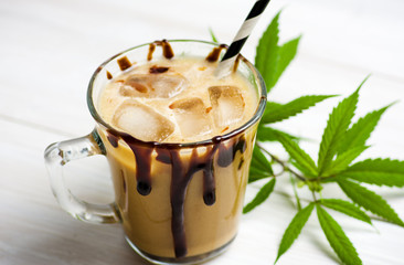 Cup of coffee with milk and marijuana leaves