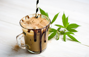 Cup of coffee with milk and marijuana leaves