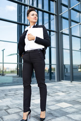 photo of a young ambitious businesswoman on the background of a modern office building