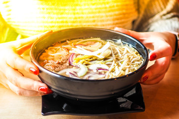  Girl holds in a hands a bowl of Vietnamese pho soup 