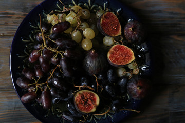 Freshly picked autumn fruits. Black and white grapes and figs on dark wooden table