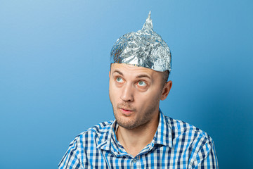 Foil hat on man. Man with a surprised face. Protects from reading think - obrazy, fototapety, plakaty