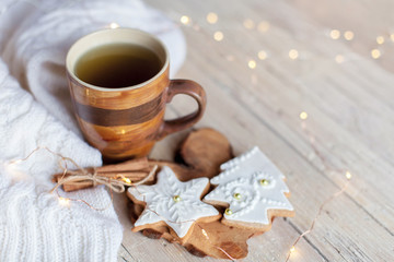 Fototapeta na wymiar Christmas still life. Mug of tea, gingerbread cookies, cinnamon at wooden background with glares. Cozy tea time with homemade sweets and cup of hot beverage. Winter food, drink, new year lights