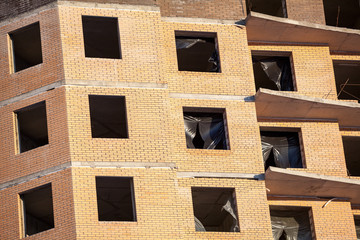 Brick wall facade with empty apertures for windows, building under construction