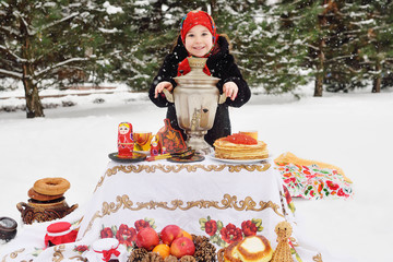 child girl in a fur coat and in a scarf in Russian style holding a large samovar in the hands of pancakes with red caviar