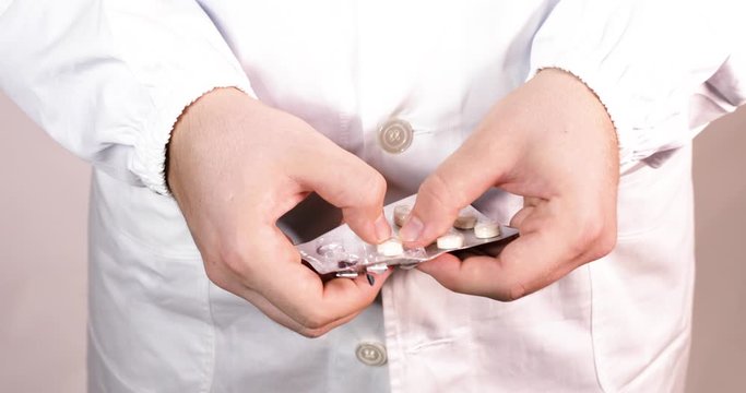 Mani di un medico mentre scartano le medicine dalla busta