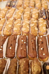 Lots of cream cakes close-up. Eclairs of different colors