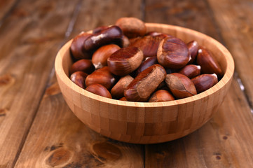 Cup of chestnuts on a wooden background. Autumn harvest and ripe fruits. Free space for text.