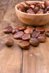 Cup of chestnuts on a wooden background. Autumn harvest and ripe fruits. Free space for text.