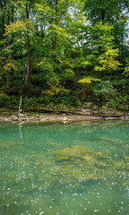 Beautiful turquoise blue mountain river. Large stones with rocks in the middle of a green forest.